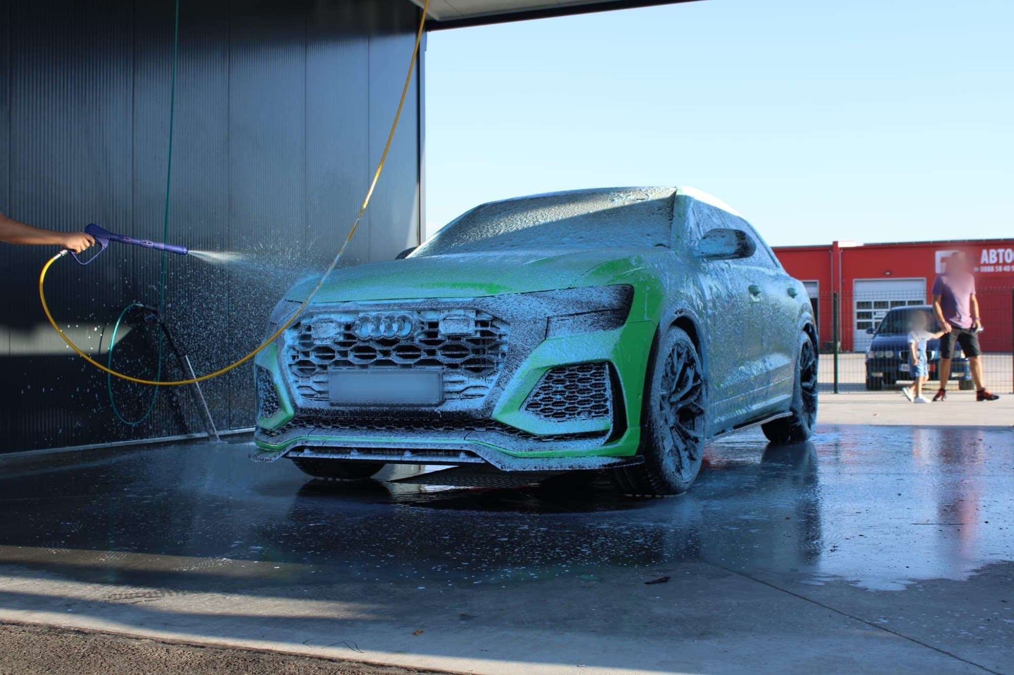 Audi RS Q8, покрито със зелена активна пяна в клетка на автомивката