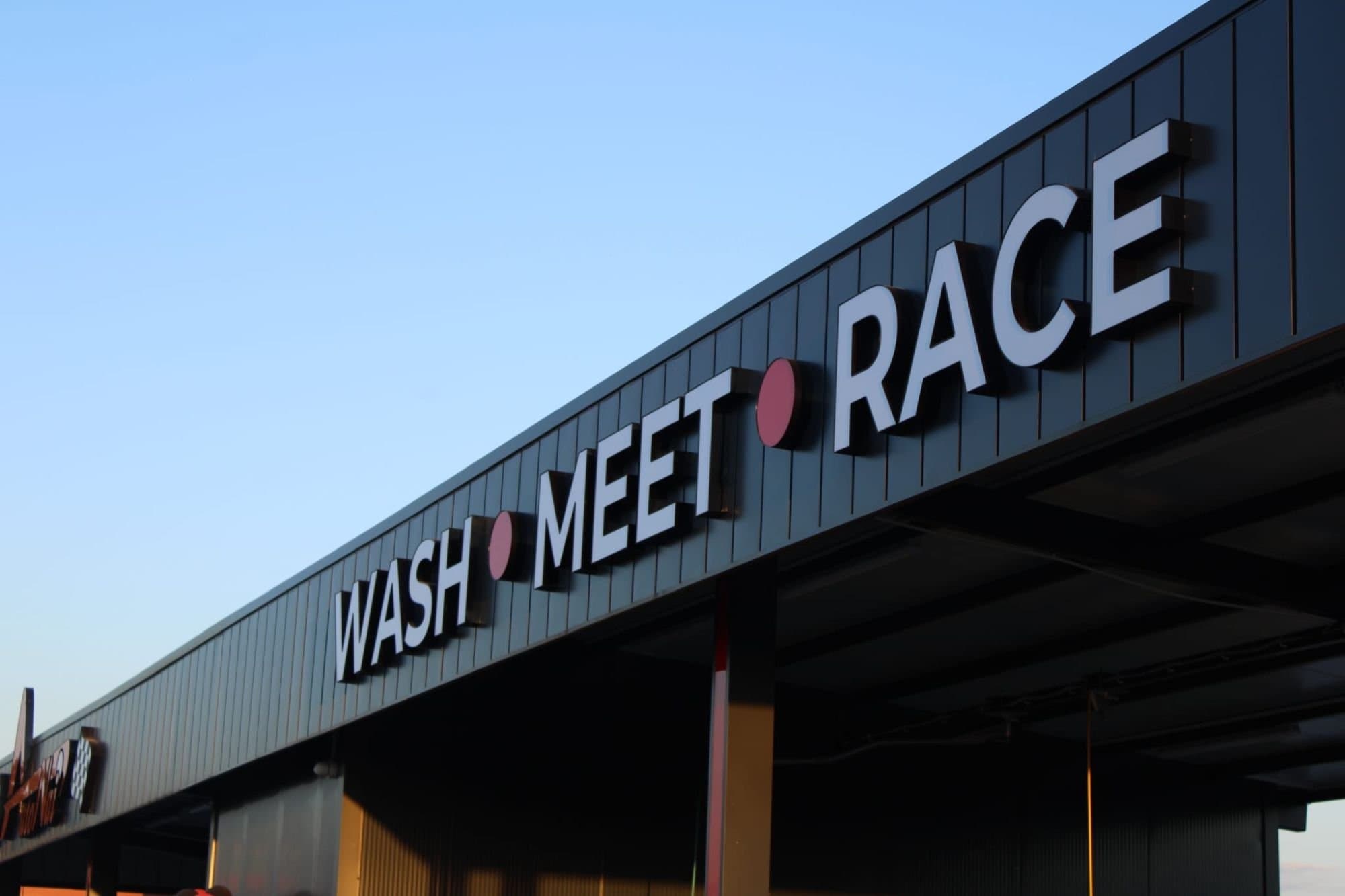 Надписът WASH • MEET • RACE на фасадата на автомивка Аутонай